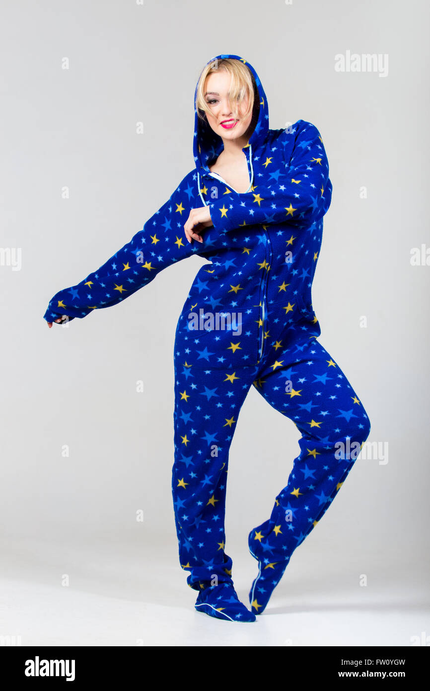Smiling beautiful girl exercising in funny blue colored dungarees nightclothes with star pattern and a hood Stock Photo