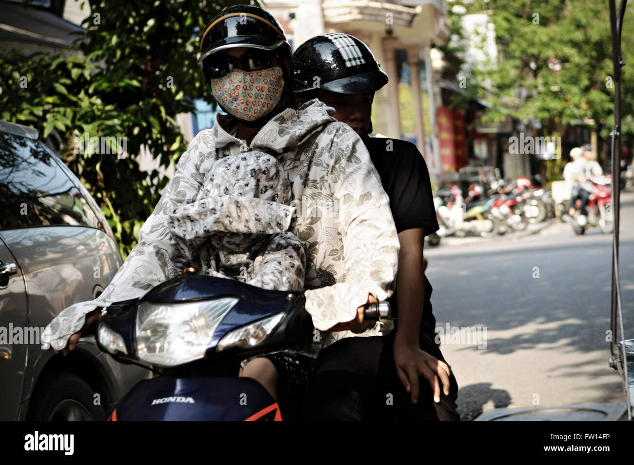 Young woman wearing a dust face mask on a scooter in the old quarter of Hanoi, Vietnam Stock Photo