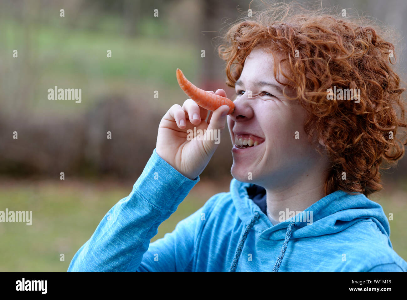 Teenager using a carrot as a long nose, Bavaria, Germany Stock Photo