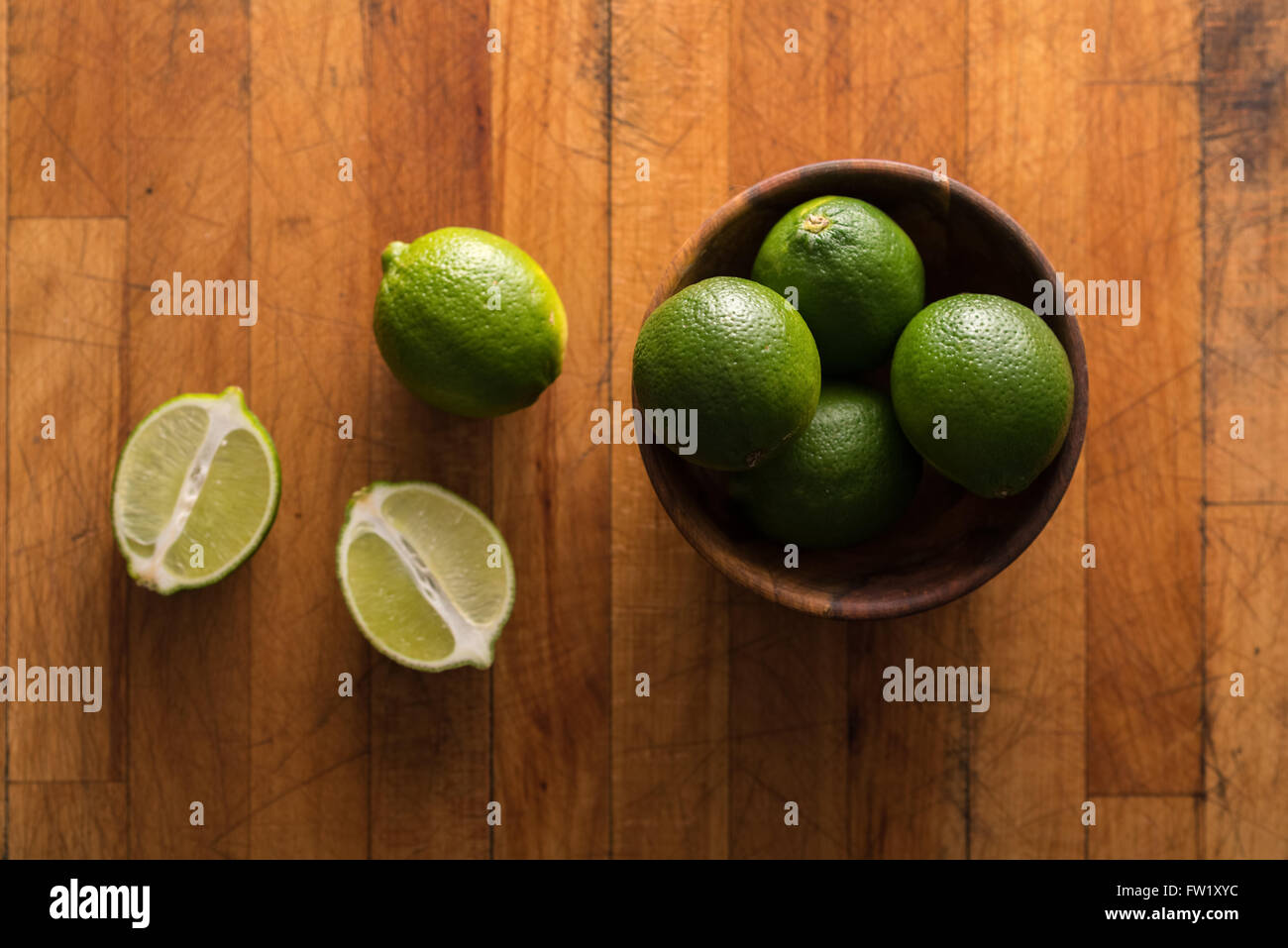 Raw whole limes in bowl on rustic wood Stock Photo