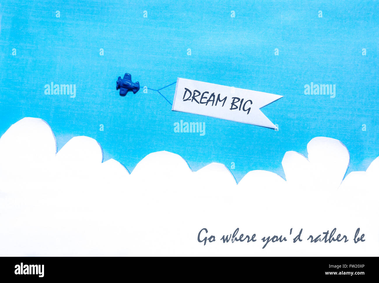Plane pulling a white banner on blue sky. Clouds. Concept. Dream big. Go where you'd rather be. Stock Photo