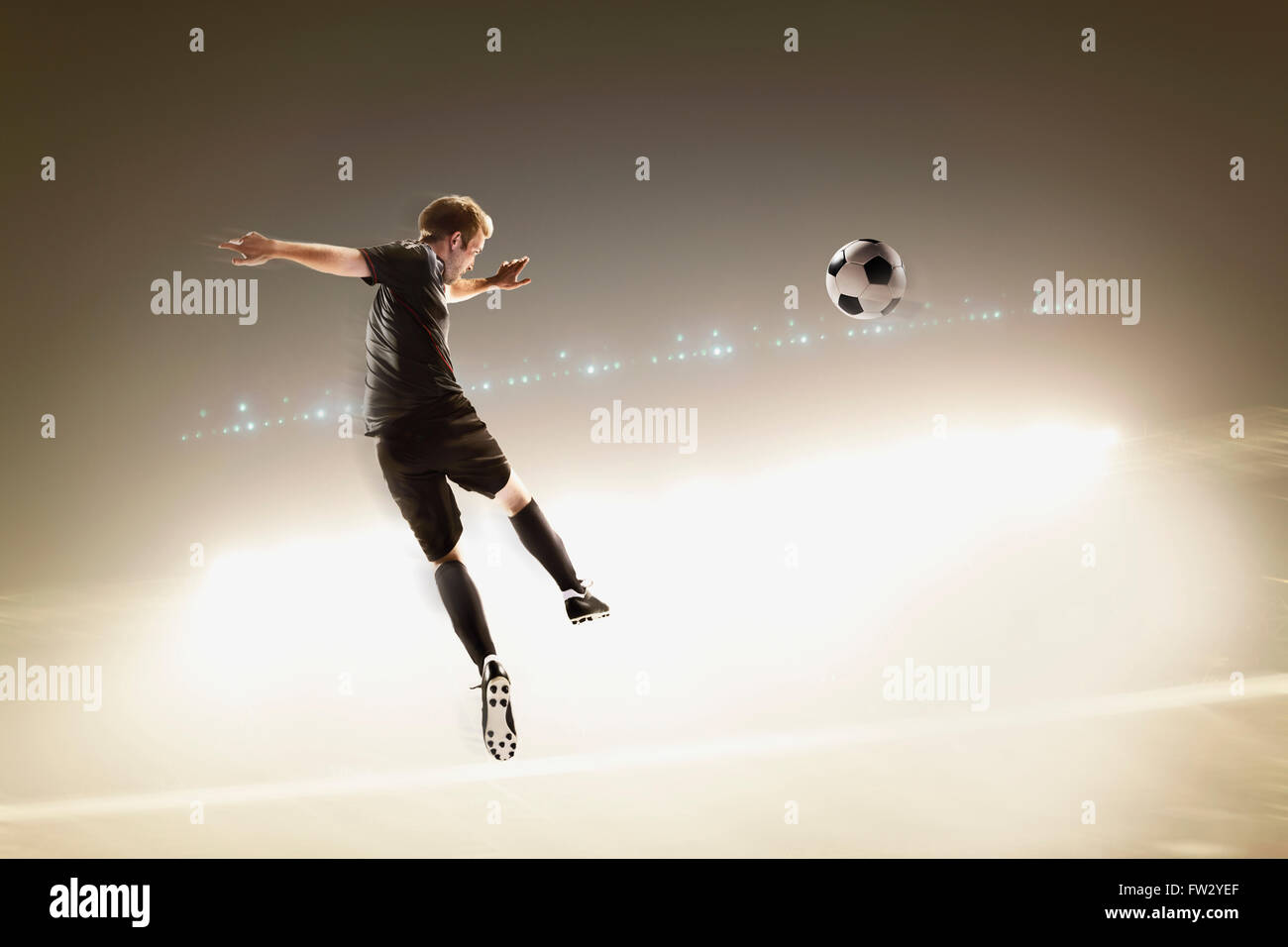 Athlete kicking soccer ball in stadium Stock Photo - Alamy