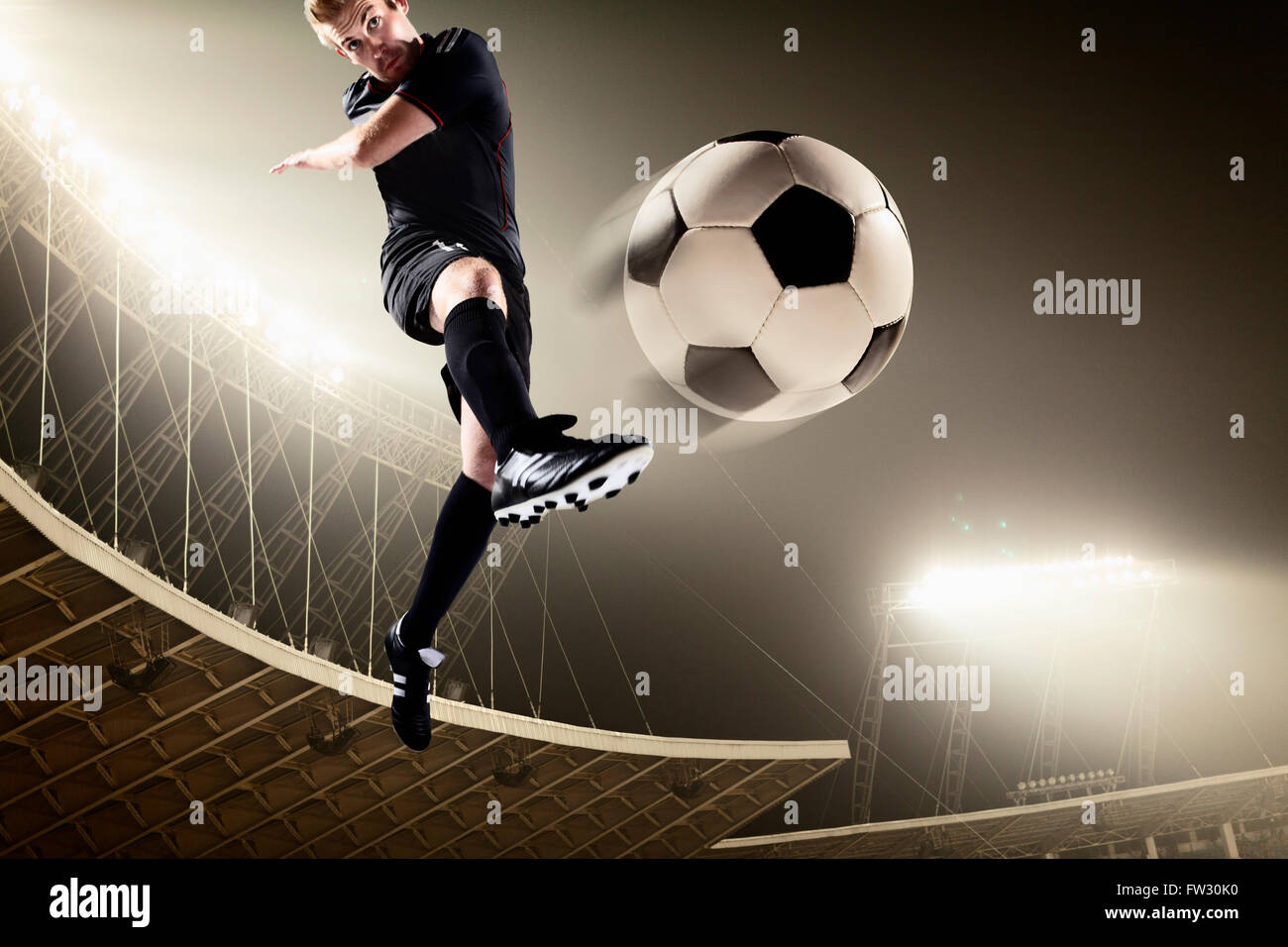 Athlete kicking soccer ball in stadium Stock Photo - Alamy