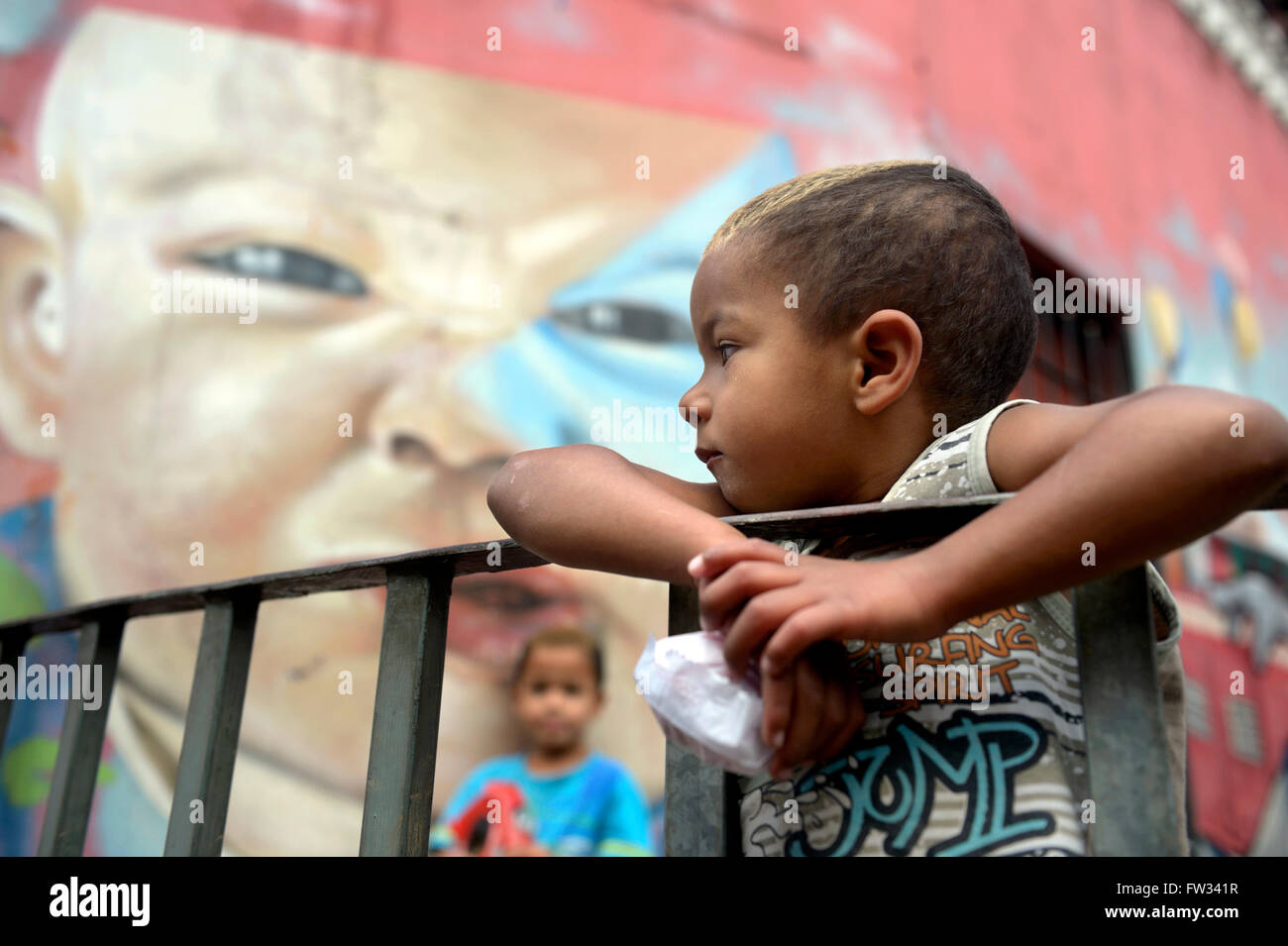 Boy in front of the graffiti of a baby's cace, favela in the Sapopemba district, Zona Sudeste, São Paulo, Brazil Stock Photo