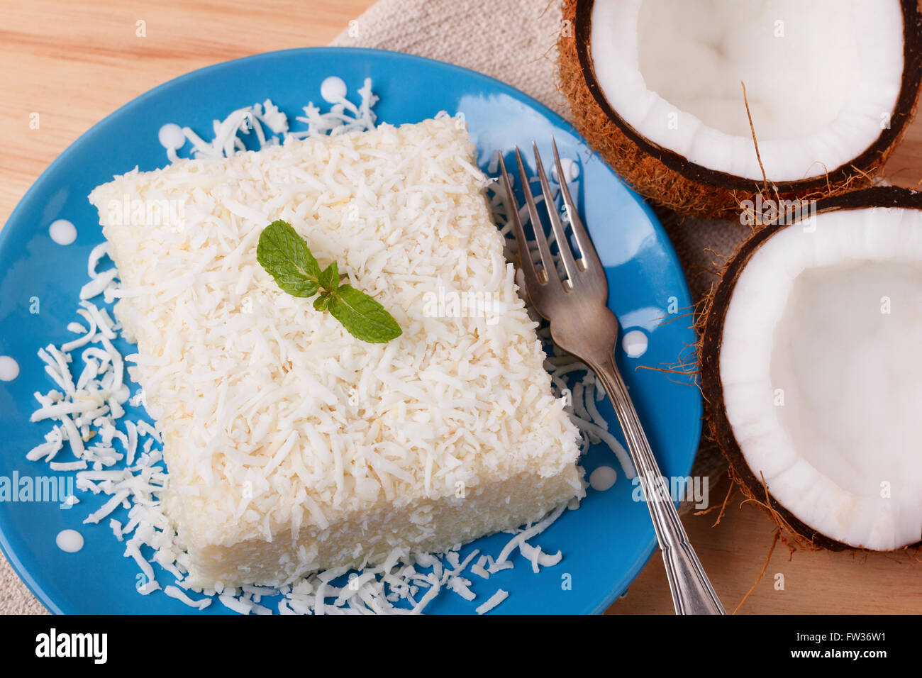 Brazilian traditional dessert: sweet couscous (tapioca) pudding (cuscuz doce) with coconut on wooden board. Selective focus Stock Photo