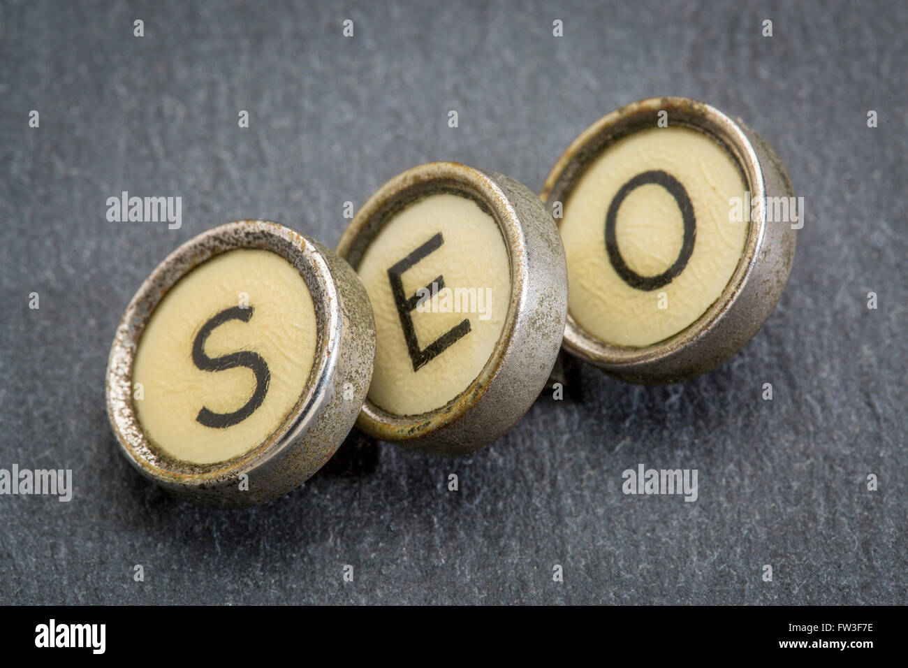 SEO acronym (search engine optimization) in old round typewriter keys against gray slate stone Stock Photo