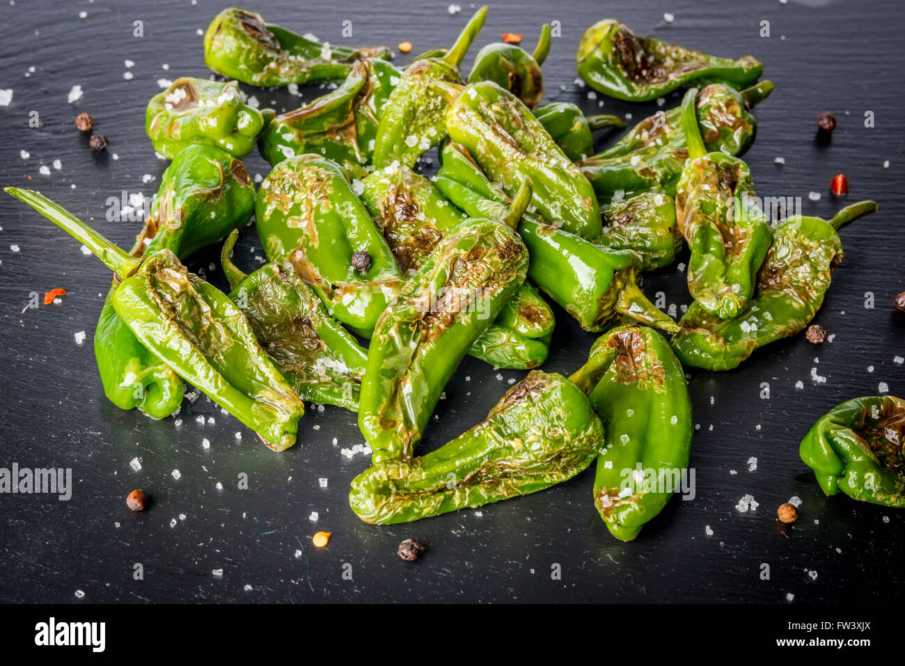 Grilled padron peppers with salt and pepper on black slate plate Stock Photo
