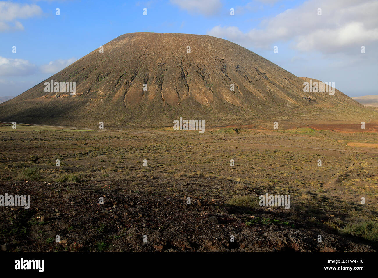 Volcanic cone with, to the left, Miguel de Unamuno monument, Tindaya, Fuerteventura, Canary Islands, Spain Stock Photo