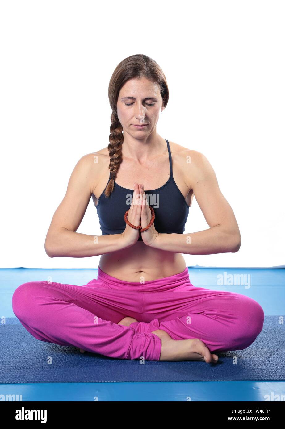Woman practicing yoga on a mat and white background Stock Photo - Alamy