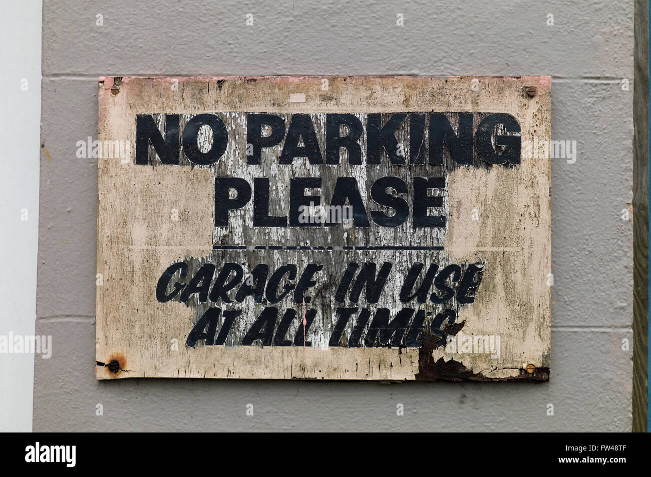 Weatherbeaten ld wooden sign 'No Parking Please' screwed to wall Stock Photo