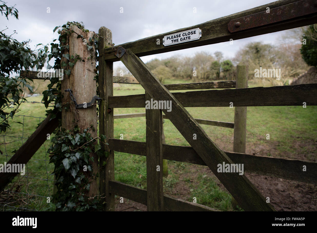 Old wooden gate entering a farmer's field with a please shut the gate sign on it. Stock Photo