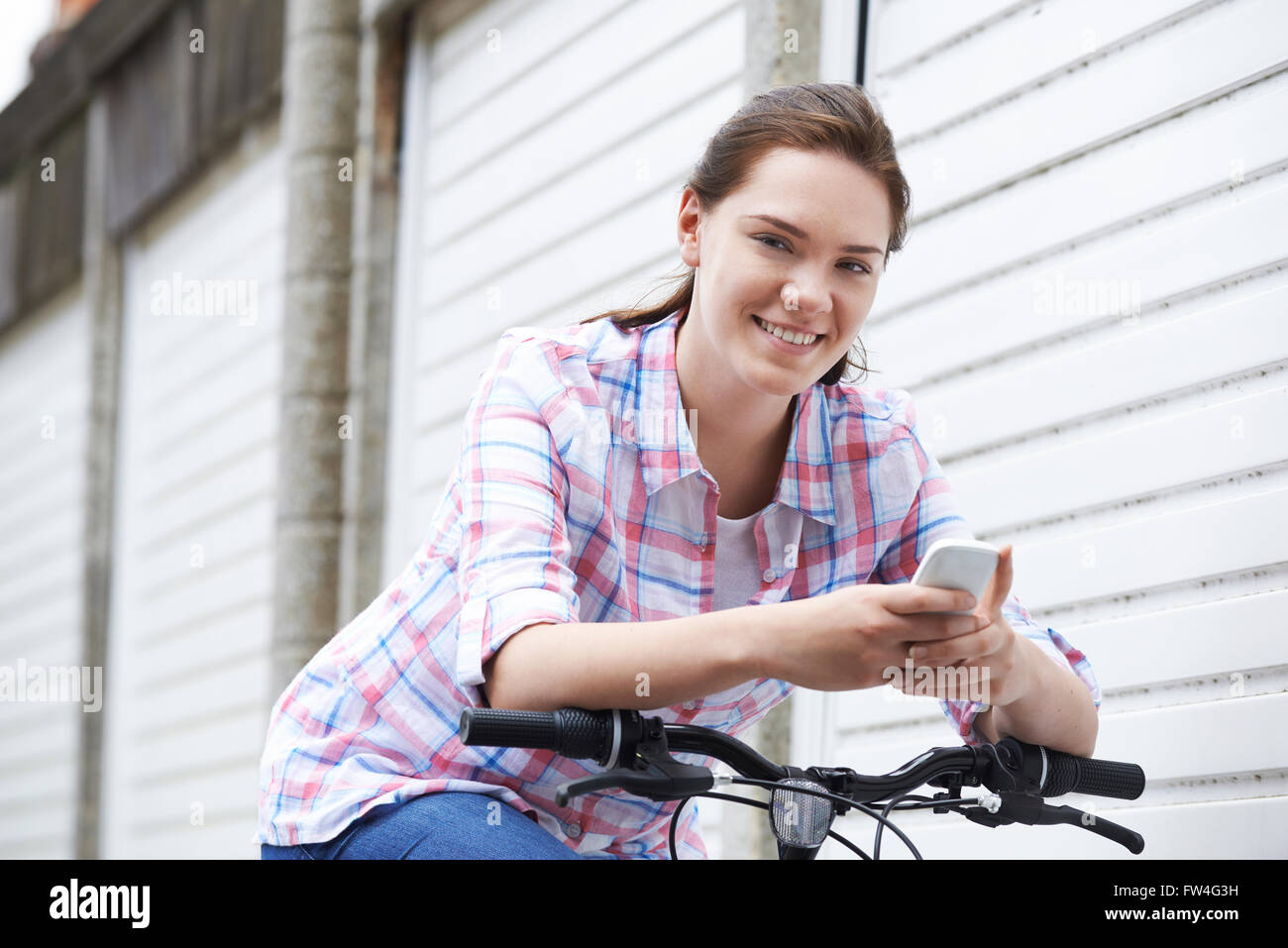 Teenage Girl On Bike Texting On Mobile Phone Stock Photo