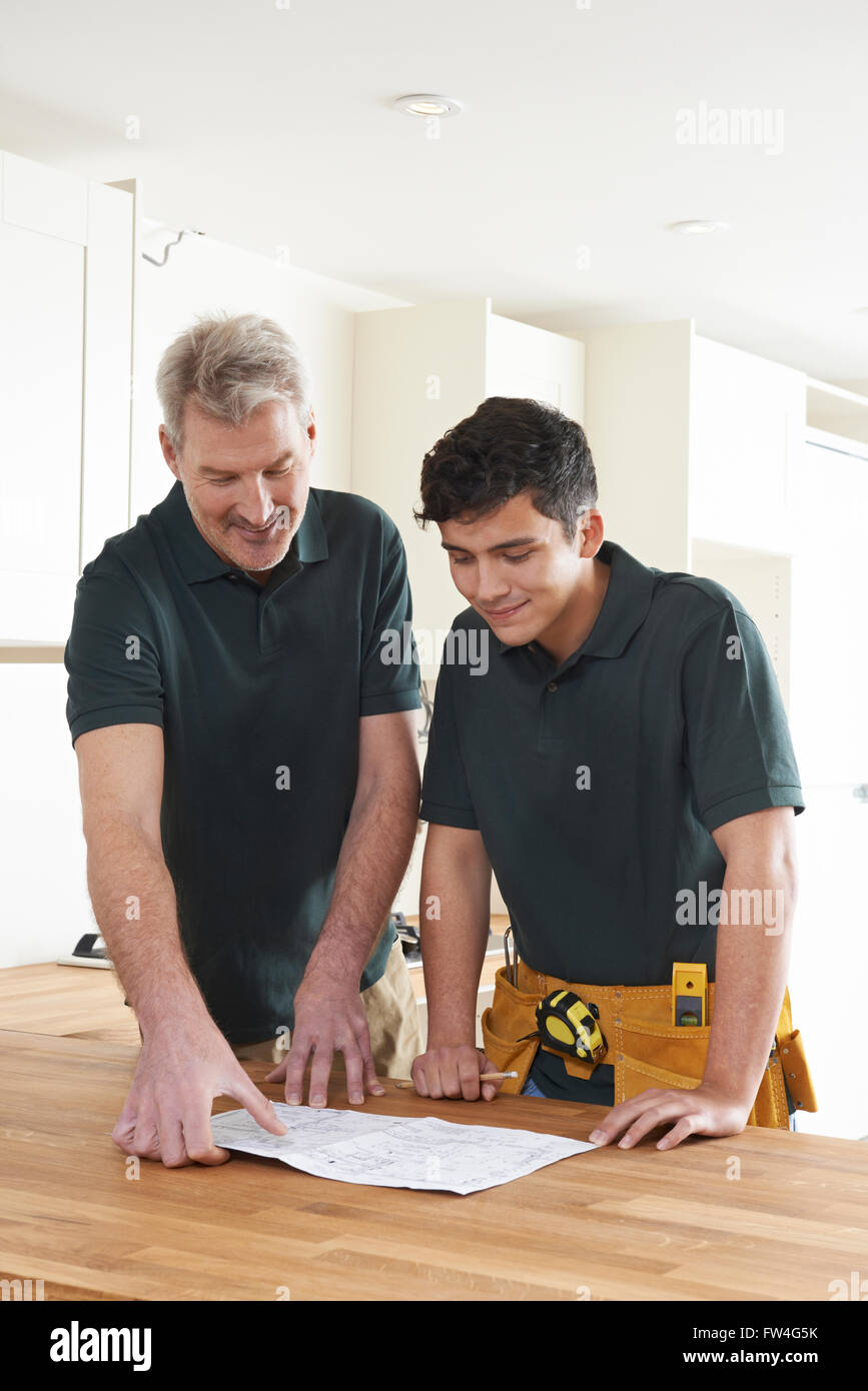 Carpenter And Apprentice Installing Luxury Fitted Kitchen Stock Photo