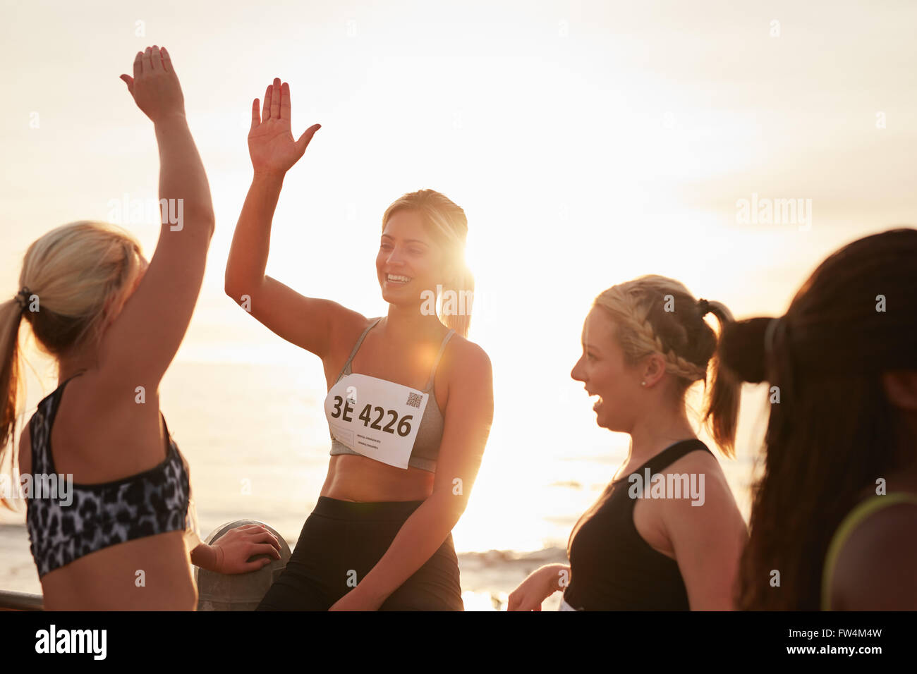 Shot of female runners high fiving each other after a race. Group of athletes giving each other high five after winning competit Stock Photo