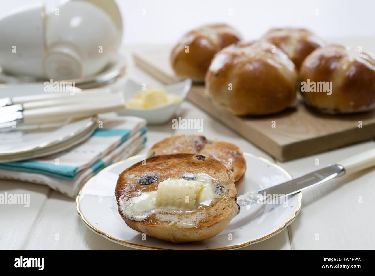 Toasted homemade hot cross buns with melting butter placed on a cream
