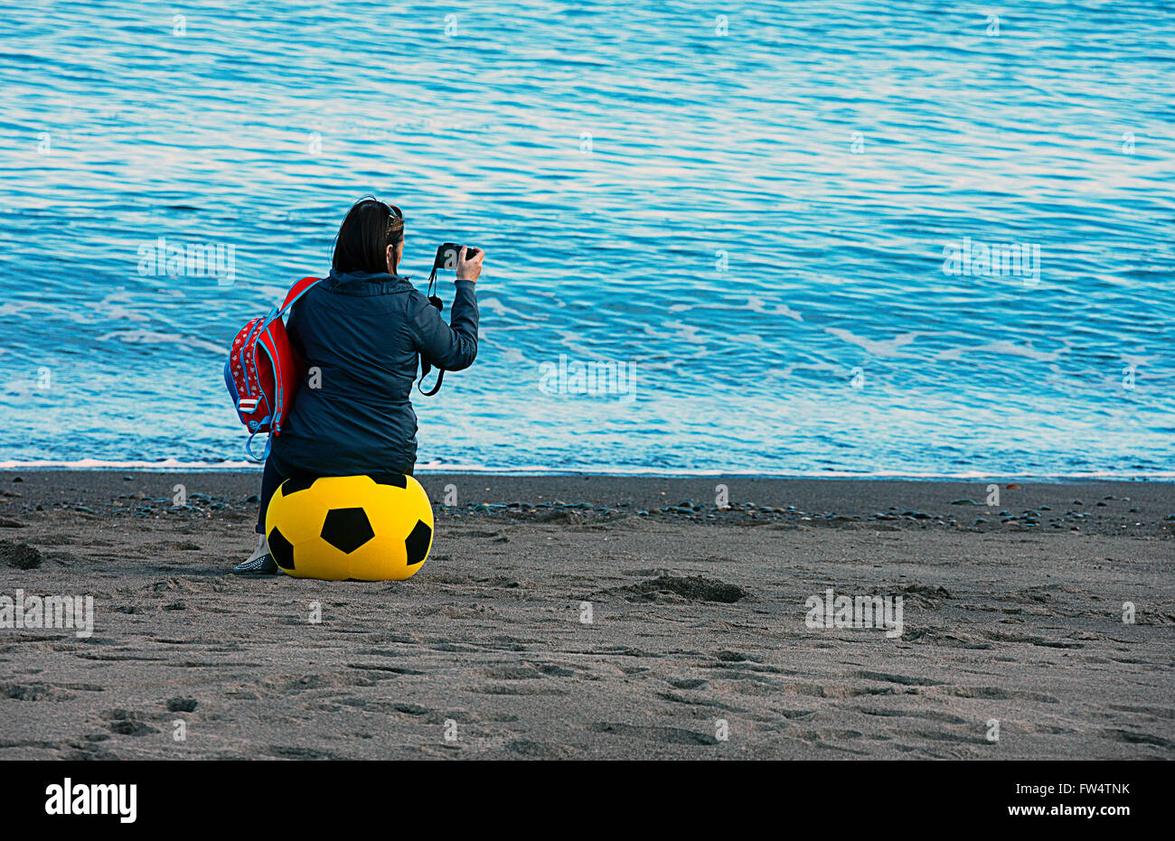 Girl sitting  on very large beach ball taken a photograph. Stock Photo