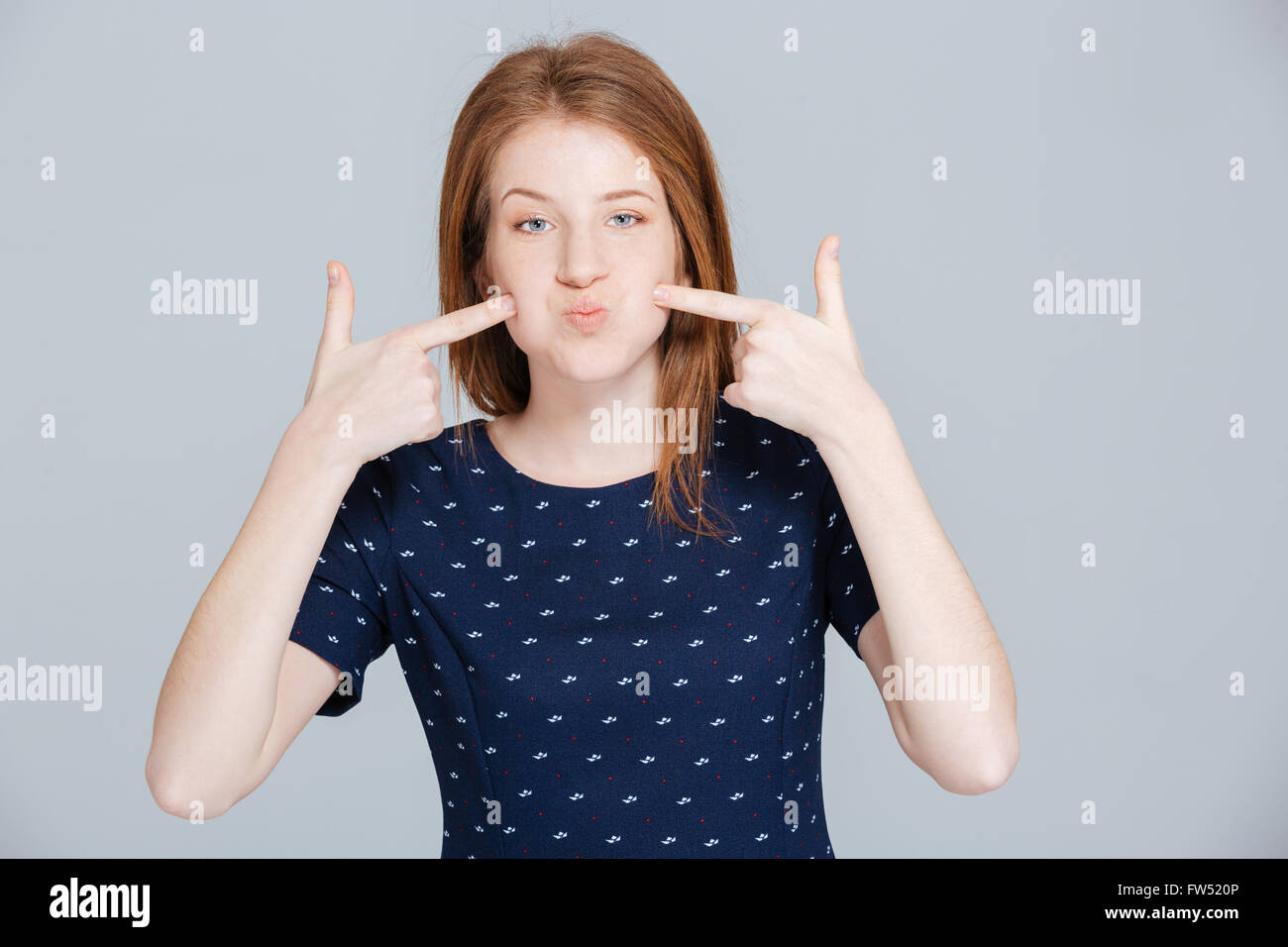 Young woman puffed out her cheeks over gray background Stock Photo