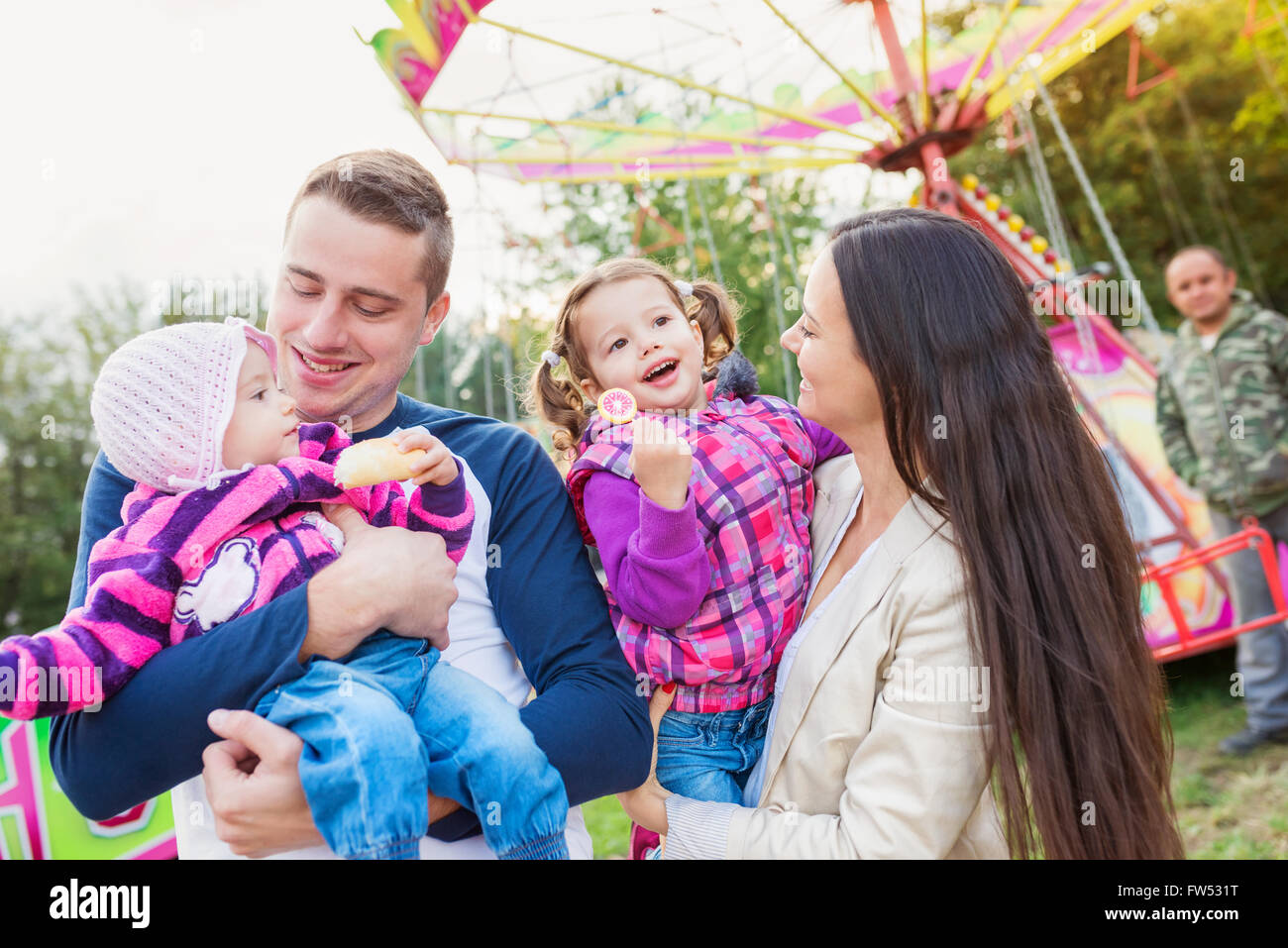 Family with little girls enjoying time at fun fair Stock Photo