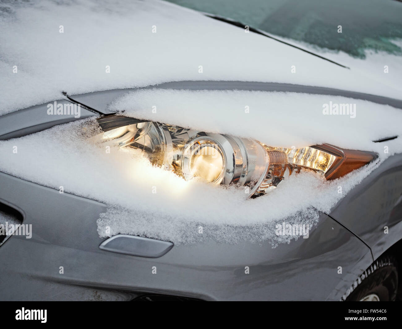 Glowing headlight of a car covered with snow as it is being driven during a  snow storm Stock Photo - Alamy