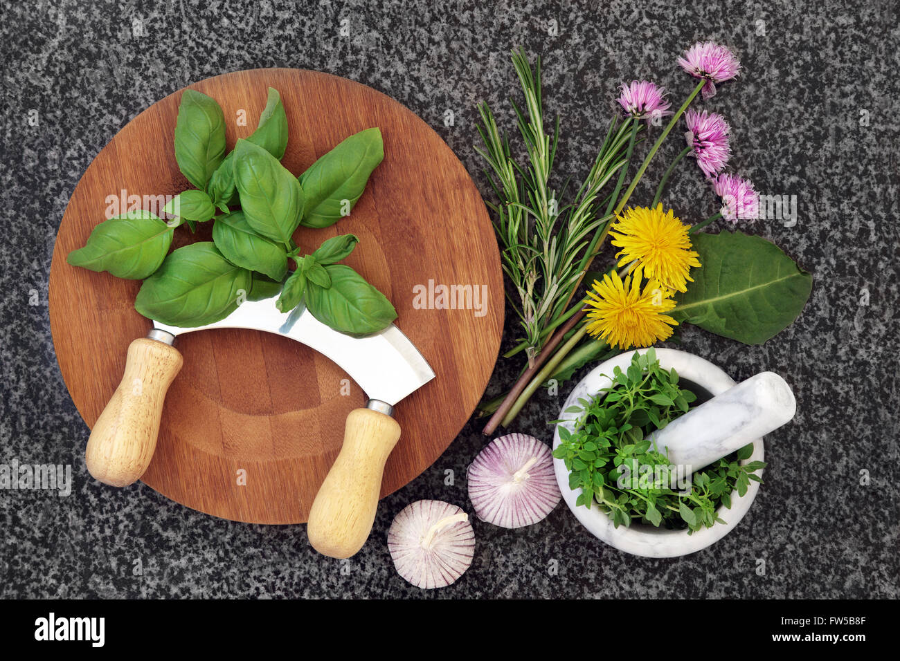 Fresh herb selection with mortar and pestle, wooden board and chopper