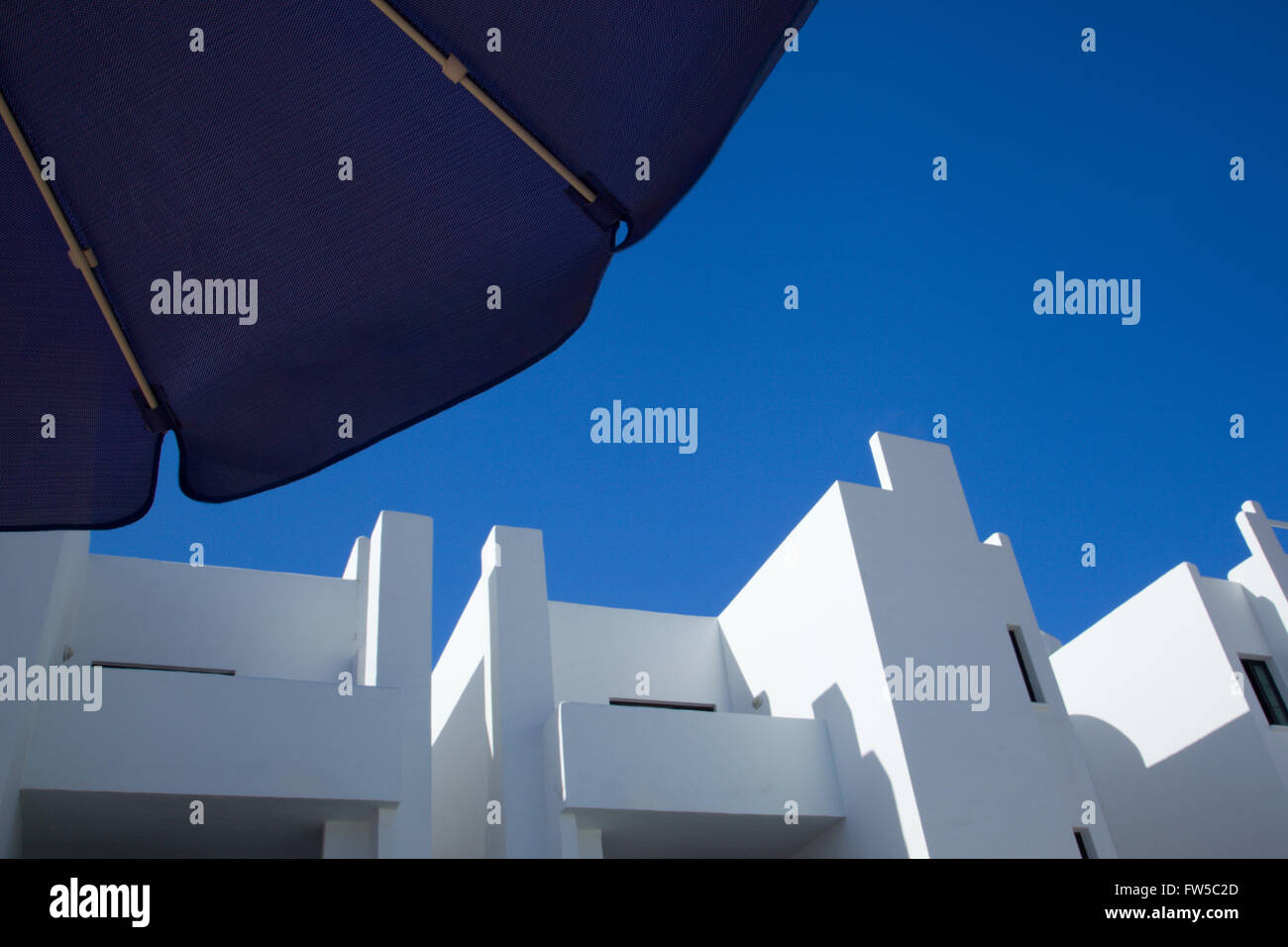 View of a clear blue sky and whitewashed holiday apartments from under