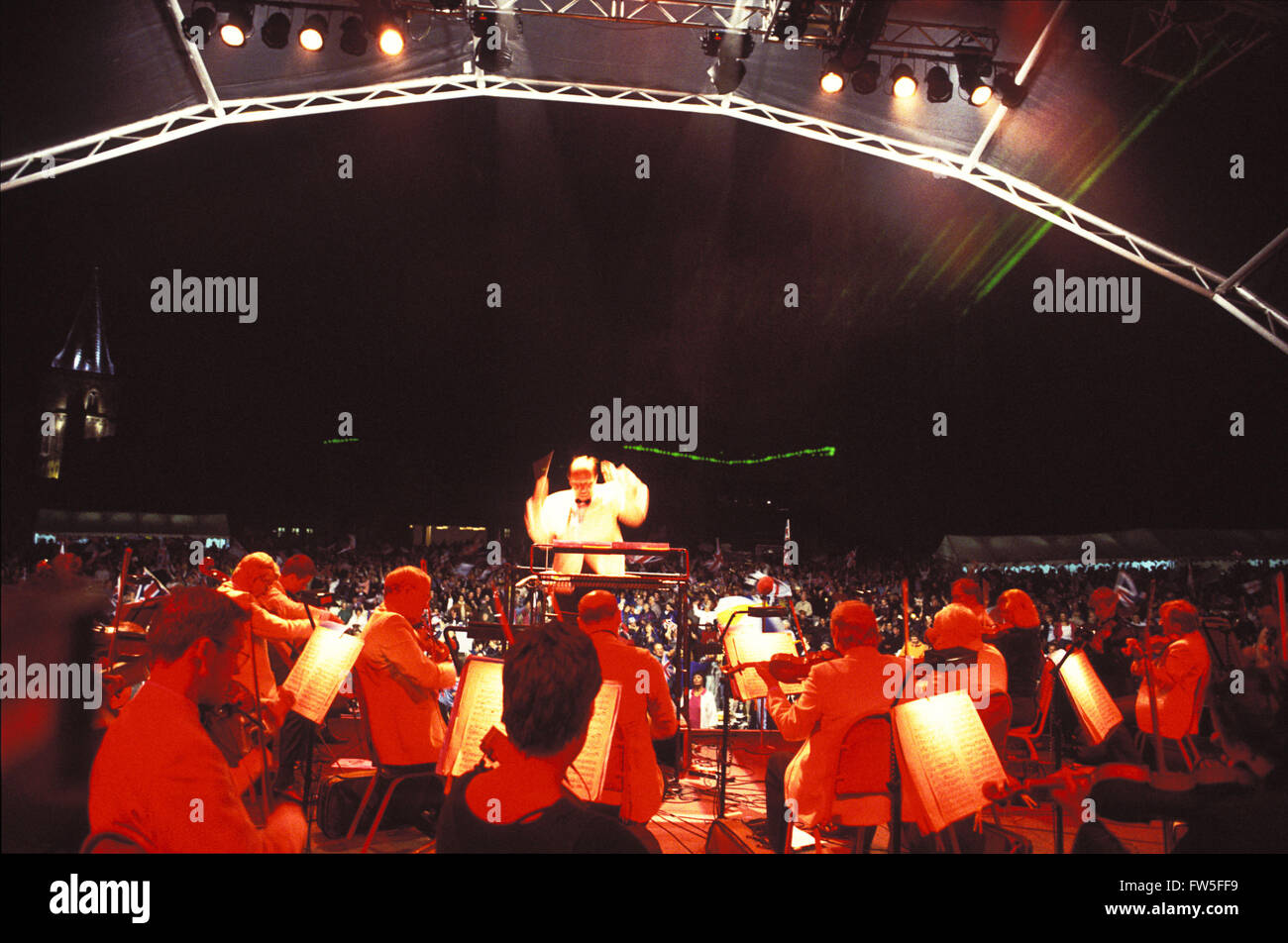 Royal Philharmonic Orchestra performing at an outdoor night floodlit concert with stage lighting