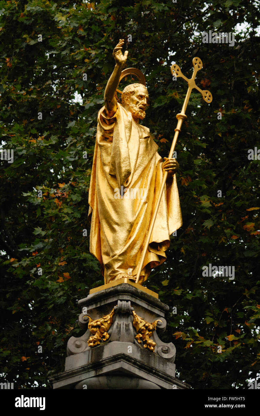 statue in St. Paul's Churchyard, St. Pauls' Cathedral. London, of St. Paul, gilt, carrying cross, on high pedestal, on site of Old St. Paul's Cross, dating from 1191 and destroyed by order of Long Parliament. Statue 1910 by Bertram Mackennal Stock Photo