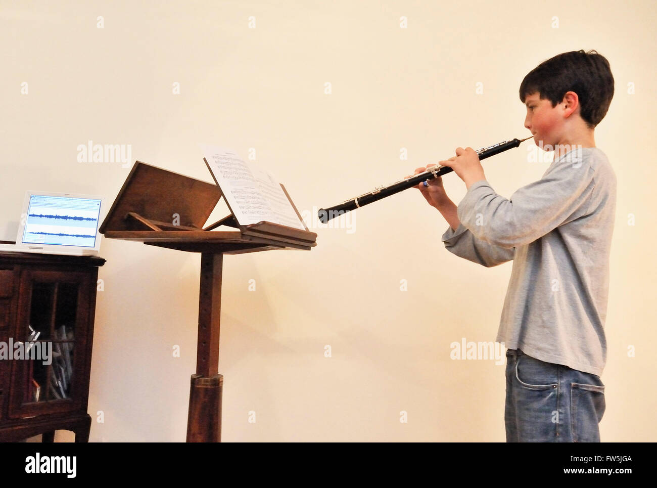 Teenage boy making a recording, playing the oboe with music stand, computer  running music recording software, and microphone Stock Photo - Alamy