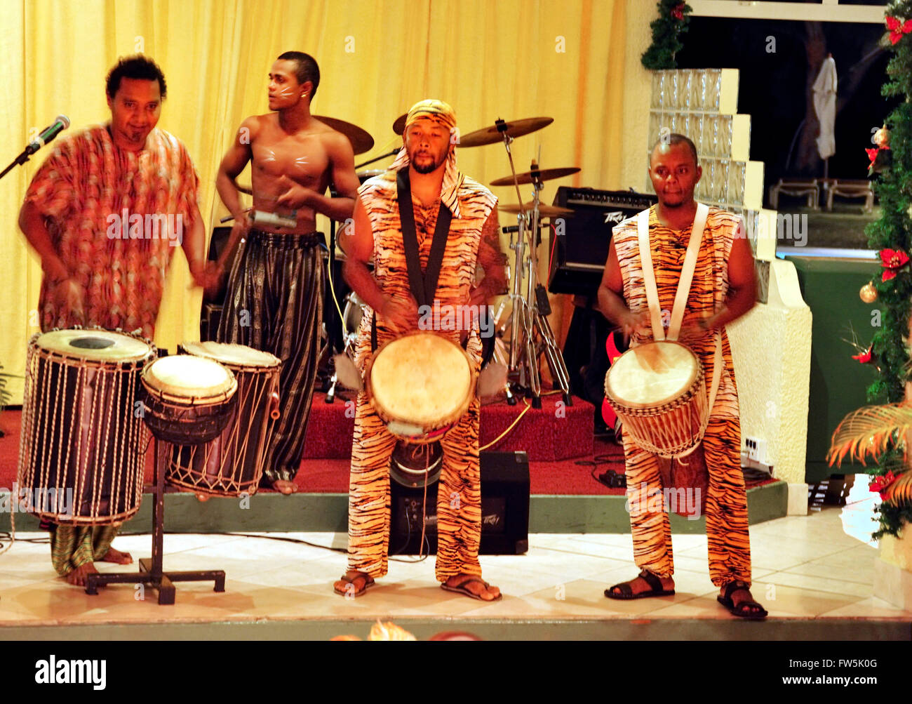 Sega drummers in Mauritius night club, playing djumbe / djembe drums from South-west Africa: dununba (large drum); sangban (medium drum); kenken, also tambour (small drum). Sega is the national song and dance of Mauritius, extremely versatile. Accompanied by distinct instruments providing rhythm only without melody, such as the ravane (a thin, wide drum of goat's skin), the maravane (pebble-filled box rattling when shaken) and the triangle, the singer sings about the tribulations of love or the humorous side of life. Stock Photo