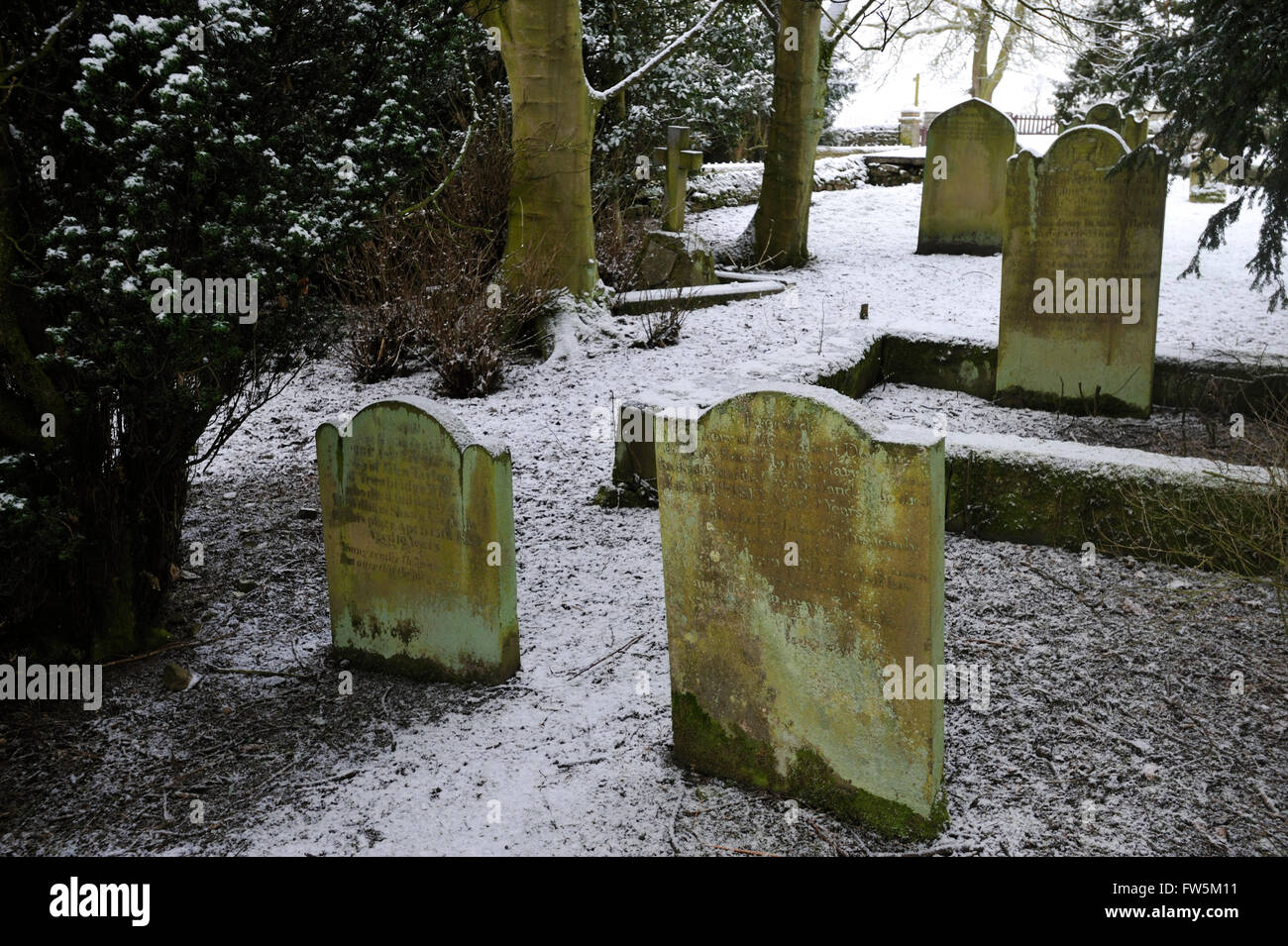the tombs under snow of John Cuthbert Dobson, aged 9, in the furthest corner of the graveyard in Bowes, on the Yorkshire Moors (now in Co. Durham), by the A66, lying next George Ashton Taylor, the original of Smike, companion to Nicholas Nickleby in the novel by Charles Dickens, English author. William Shaw, headmaster, is buried along with 8 pupils from William Shaw's Academy, one of several schools in the area offering tuition 'without holidays' to unwanted children, often from London. Dickens made a special visit through thick snow in February 1838, and denounced the cruelty and appalling c Stock Photo