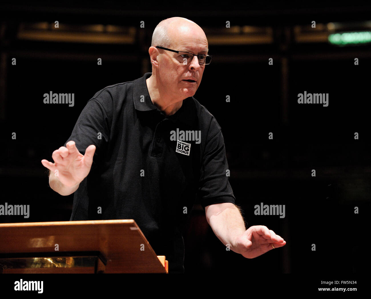 Brian Kay, conductor, in rehearsal with The Really Big Chorus and orchestra for Concerts From Scratch (and wearing T-shirt logo), Royal Albert Hall, London: Handel's Messiah. Has just taken over the musical directorship of the RBC. Conductor, presenter for BBC Radio and Televsion, a founder member 1978 and bass singer with The King's Singers, conductor of Vaughan Williams' Leith Hill Musical Festival in Surrey; he also sang the voice of Papageno in the Hollywood movie ÔAmadeus' (his wife, the soprano Gillian Fisher sang Papagena), has been the lowest frog on a Paul McCartney single, one of the Stock Photo