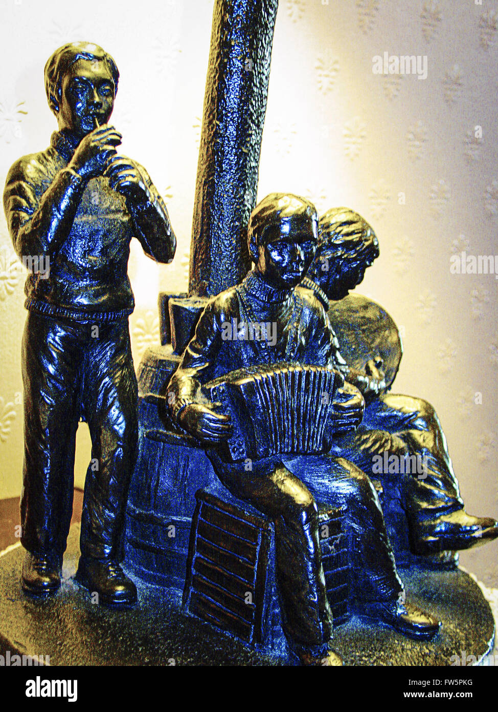 Irish musicians lamp; cast iron lampstand showing three Irish folk musicians, playing tin whistle, bodhran, accordeon Stock Photo