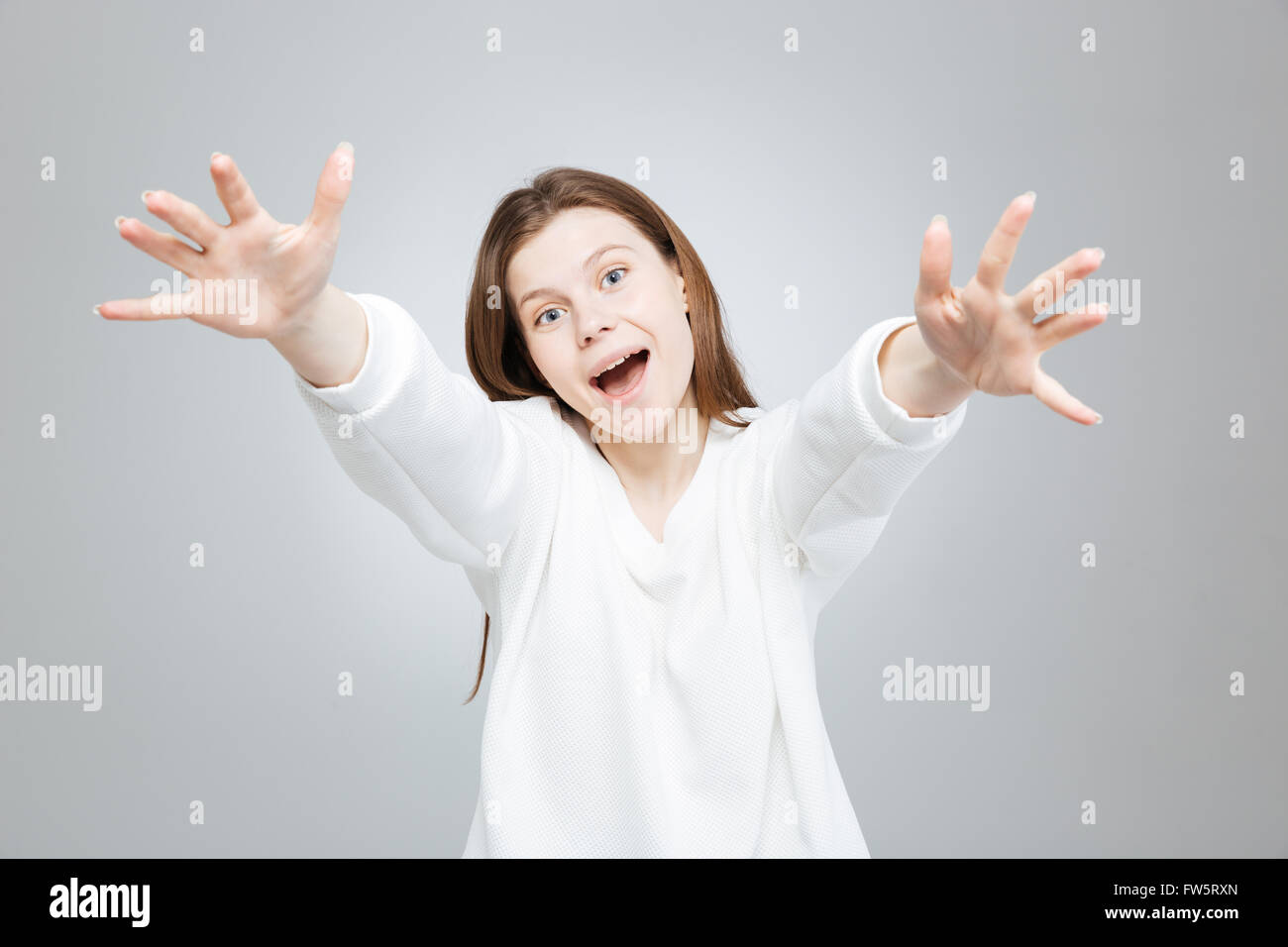 Cheerful excited teenage girl smiling and reaching hands over gray Stock Photo