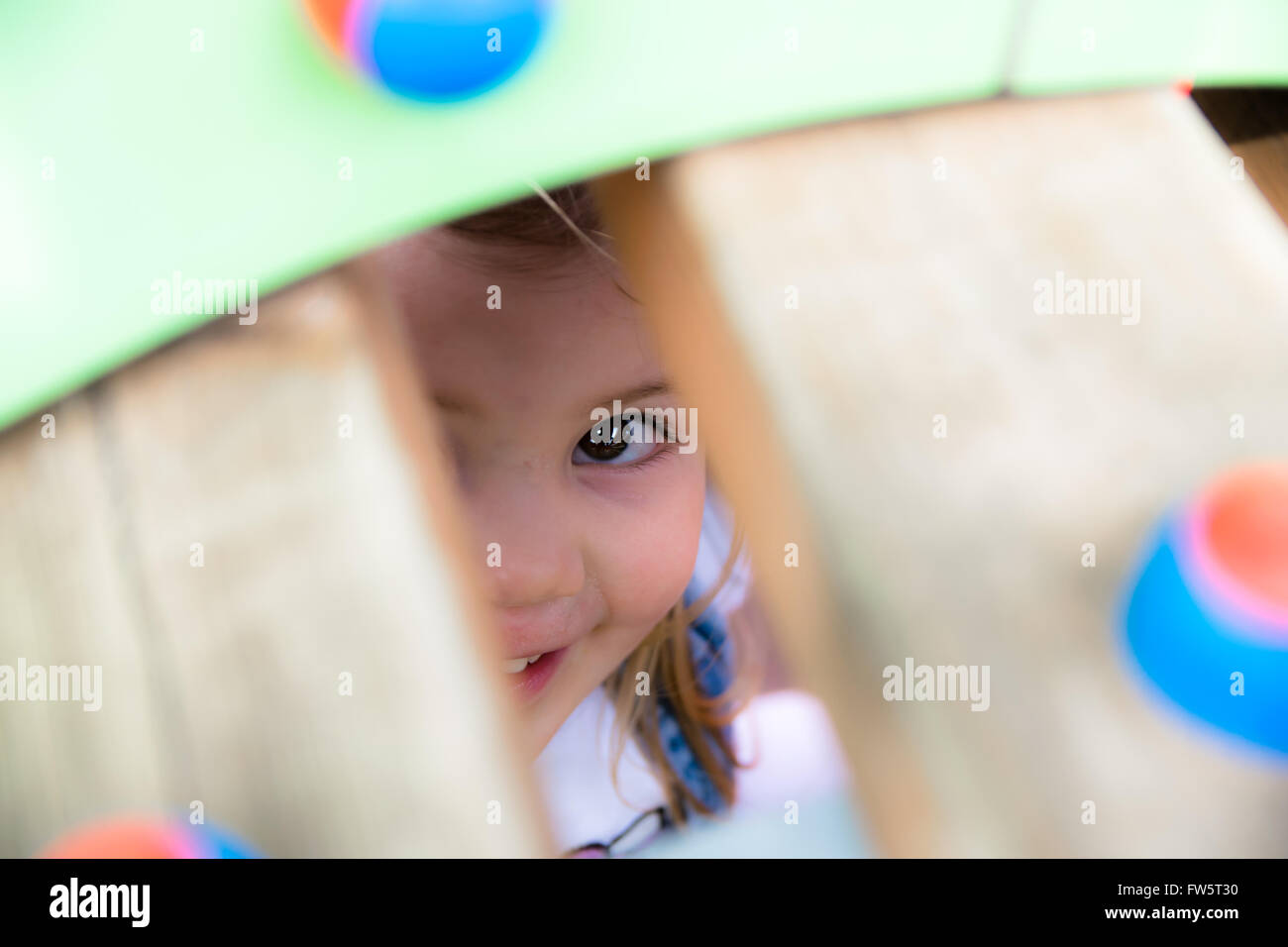Little girl playing hide and seek in a playground. Stock Photo