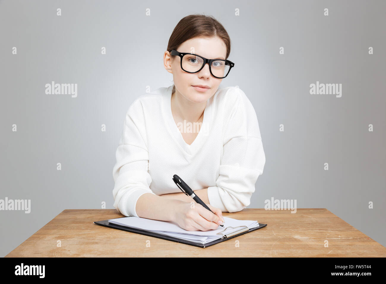 Beautiful pensive teenage girl in glasses sitting at the table and ...