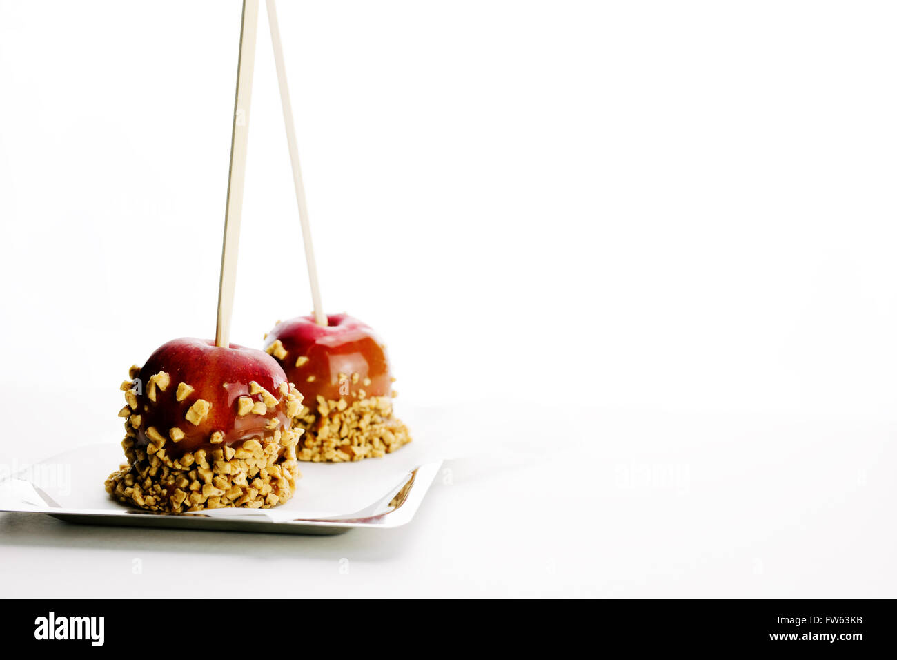 Two caramel apples with toffee brickle resting on parchment paper