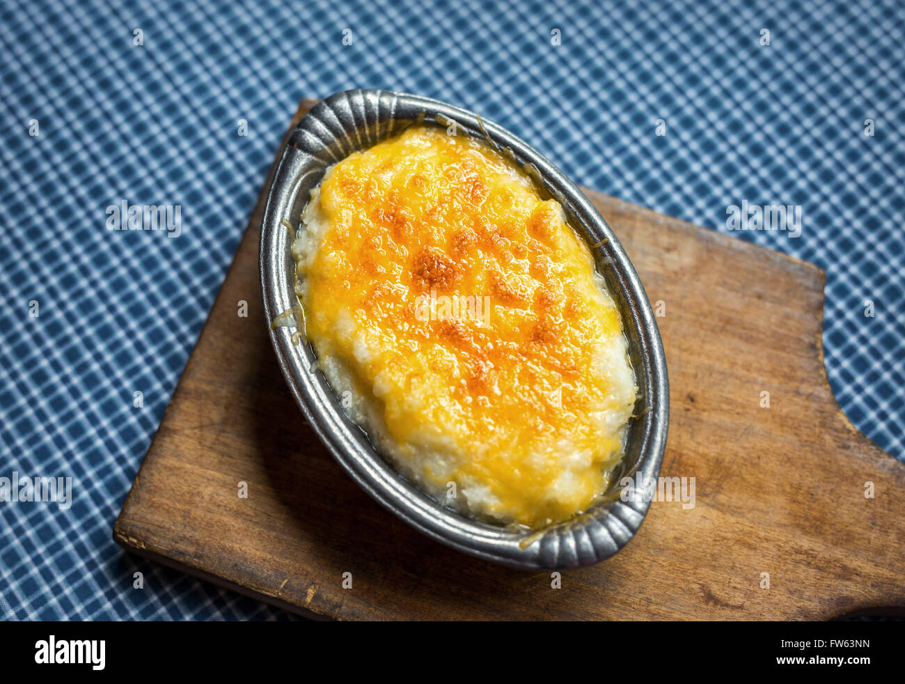 Overhead shot of hominy grits baked with cheddar cheese in a small antique pewter serving bowl. Stock Photo