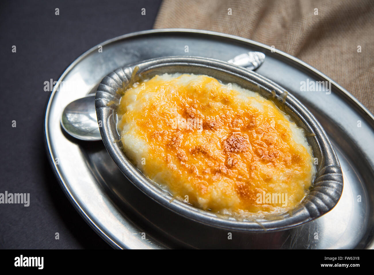 Overhead shot of hominy grits baked with cheddar cheese in a small antique pewter serving bowl. Stock Photo