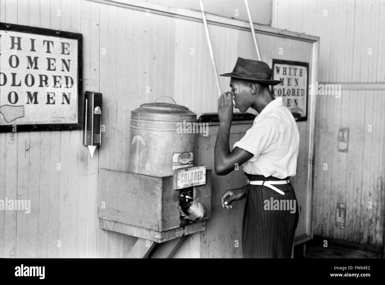 Segregation, USA. Black man drinking at a water cooler with a 'Colored' sign below, Streetcar Terminal, Oklahoma City, Oklahoma, USA. Photo by Russell Lee, 1939. Stock Photo