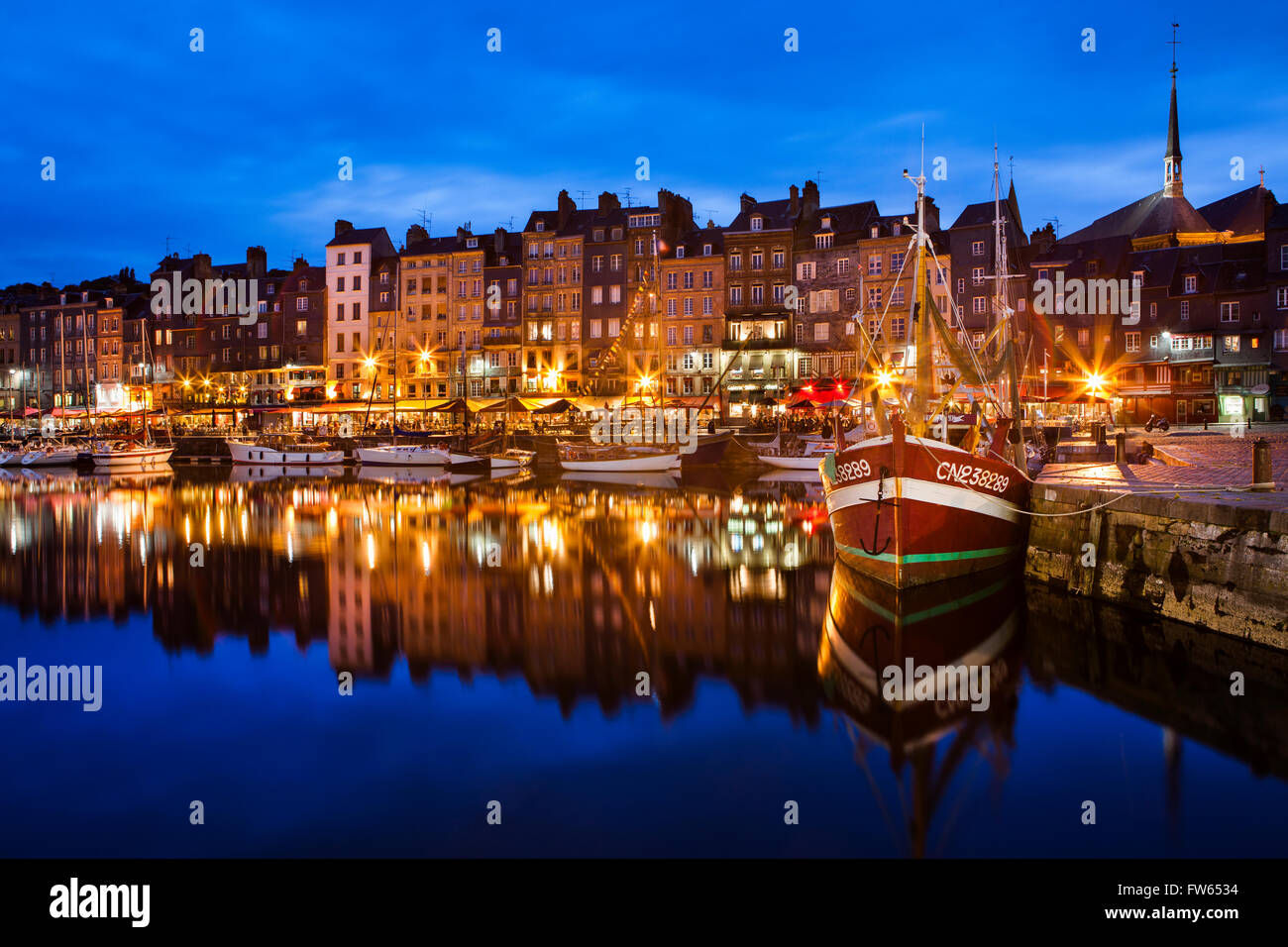 Houses and fishing boats at the old harbor with reflections in calm water in the evening, Vieux Bassin, Honfleur, Calvados Stock Photo