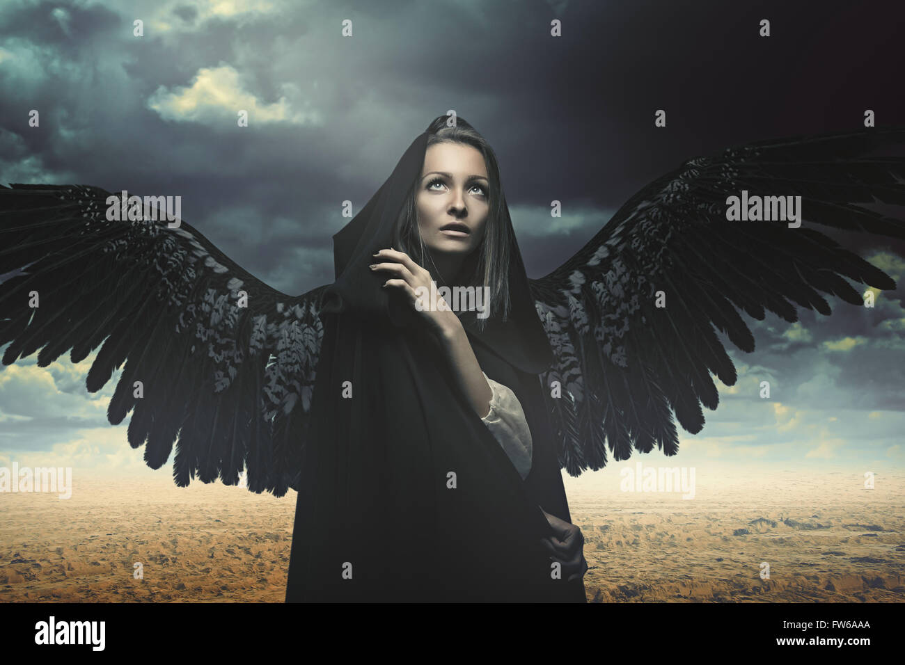 Fallen angel in a desert and stormy landscape. Fantasy and surreal Stock Photo
