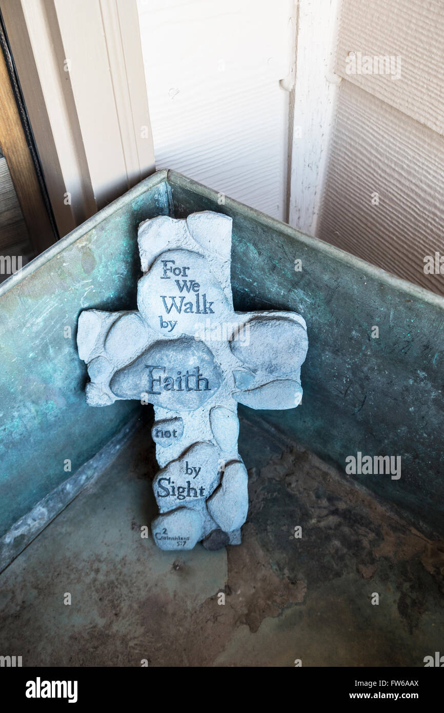 A Christian religious cross with a verse from Corinthians 2 sitting on a front porch. Stock Photo