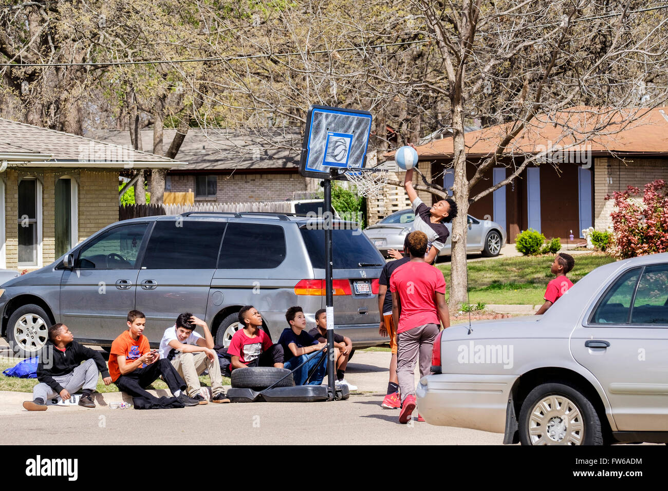 Teen and pre-teen boys gather and play basketball on the street in Oklahoma City, Oklahoma, USA. Stock Photo