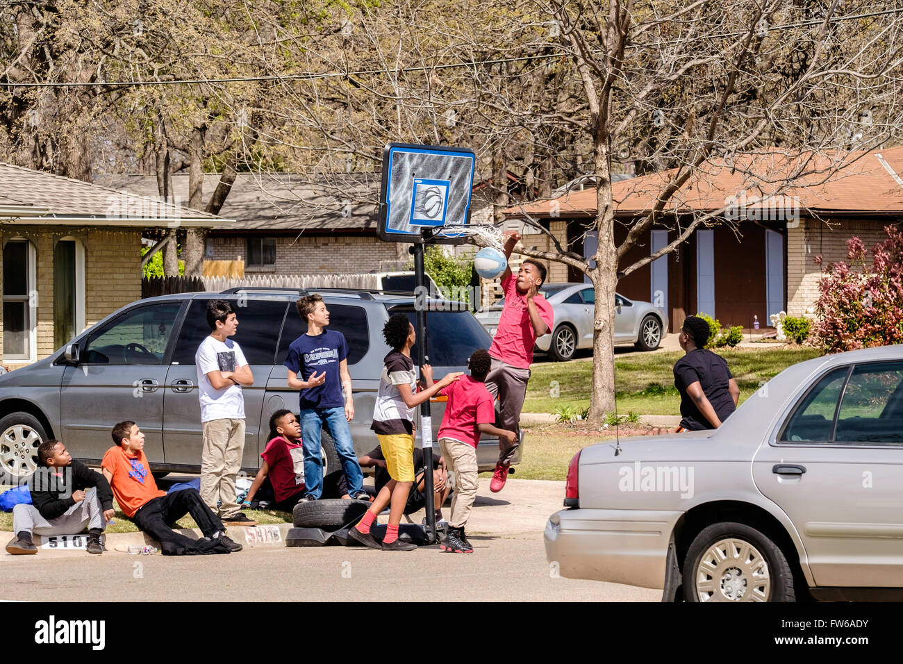 Teen and pre-teen boys gather and play basketball on the street in Oklahoma City, Oklahoma, USA. Stock Photo