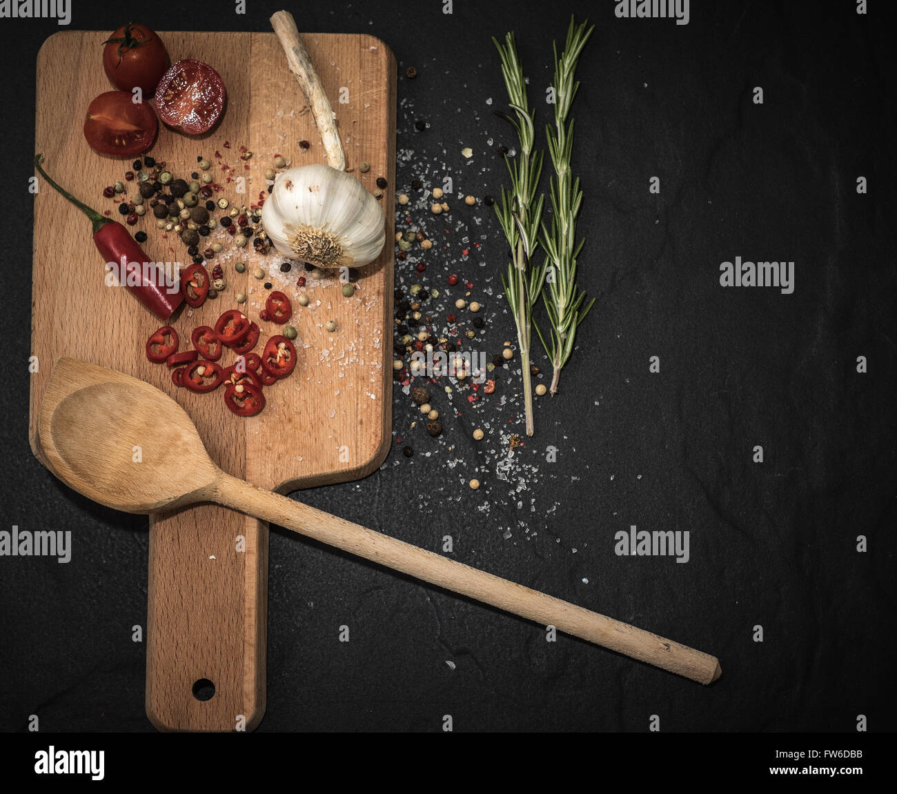Rustic wooden chopping board on a Black slate background red chili ...