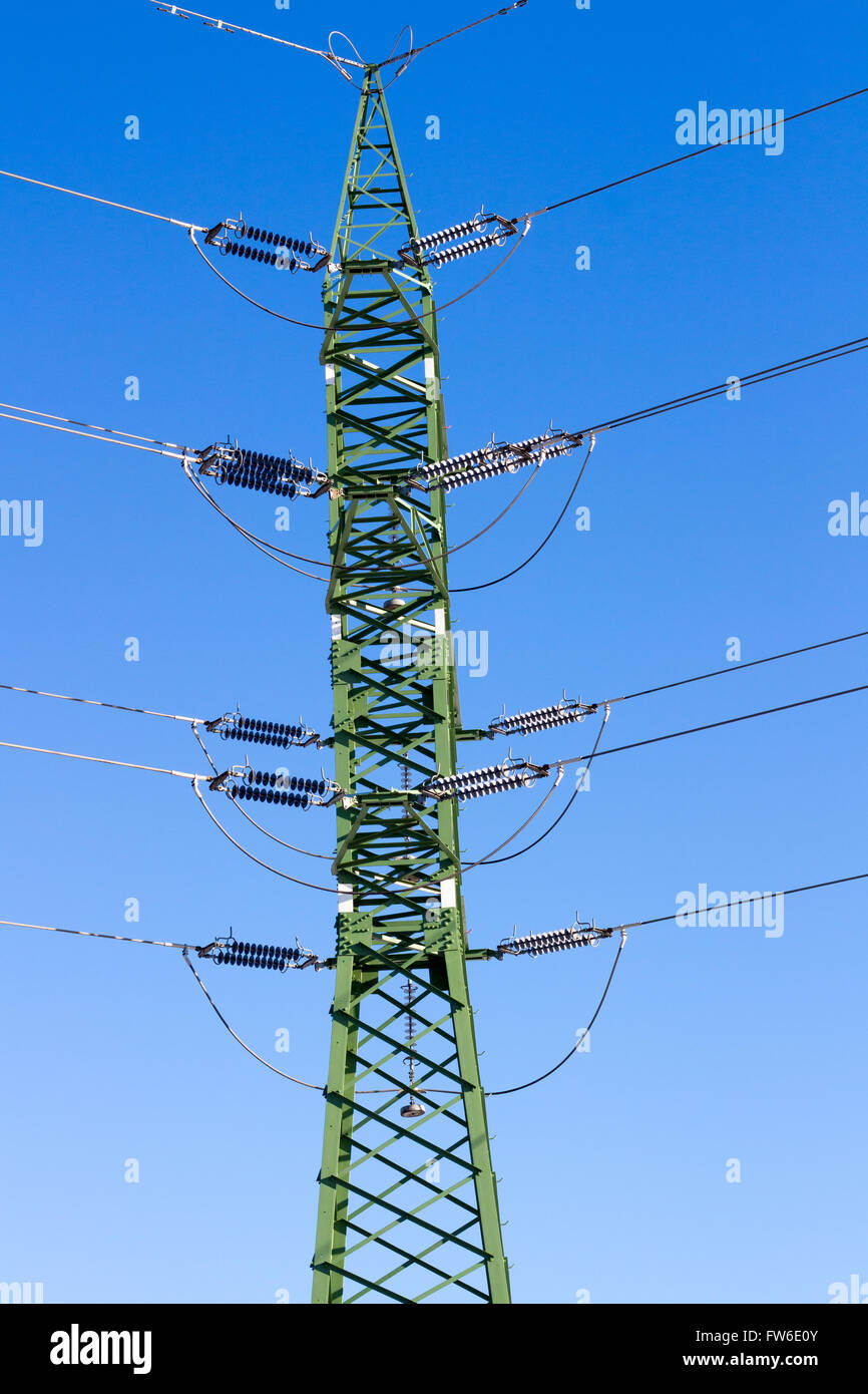 a high voltage power pylons against blue sky and sun rays Stock Photo