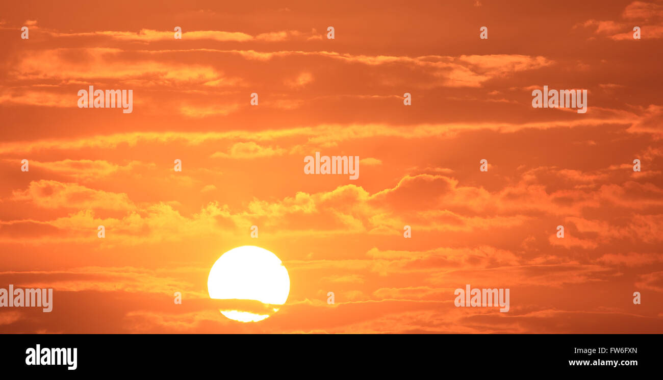 Sunrise / sunset with orange and red sky filled with clouds Stock Photo