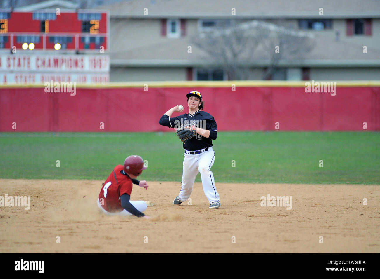High school second baseman backs off the second base bag after retiring a sliding runner prior to throwing onto first base. USA. Stock Photo