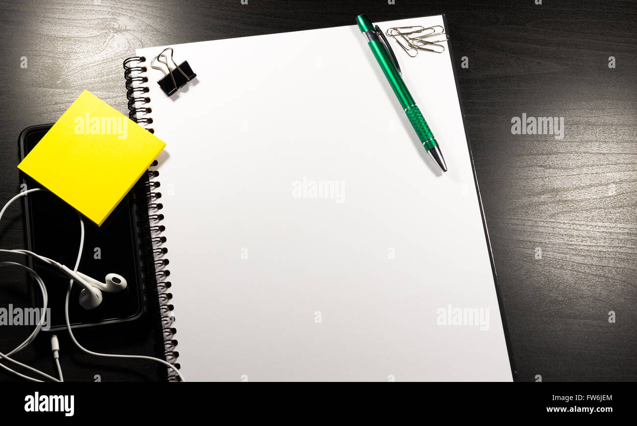 Notebook with blank paper, color sticky notes, pen and clips on a wooden table Stock Photo