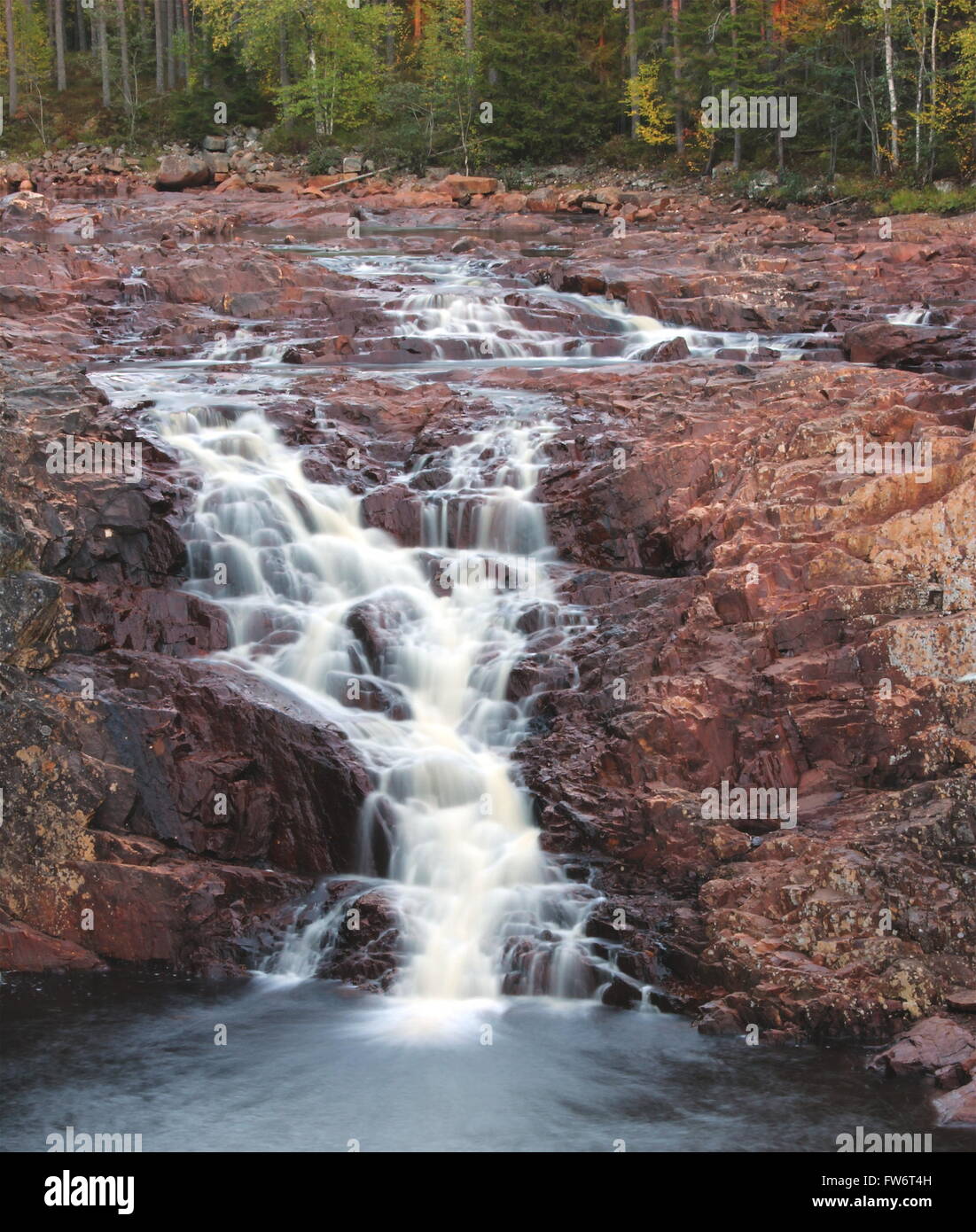 Long exposure of a waterfall (Brattfallet) on red rocks, in Värmland, Sweden. Stock Photo